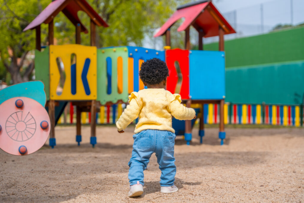 Toddler walking toward a brightly colored playground
